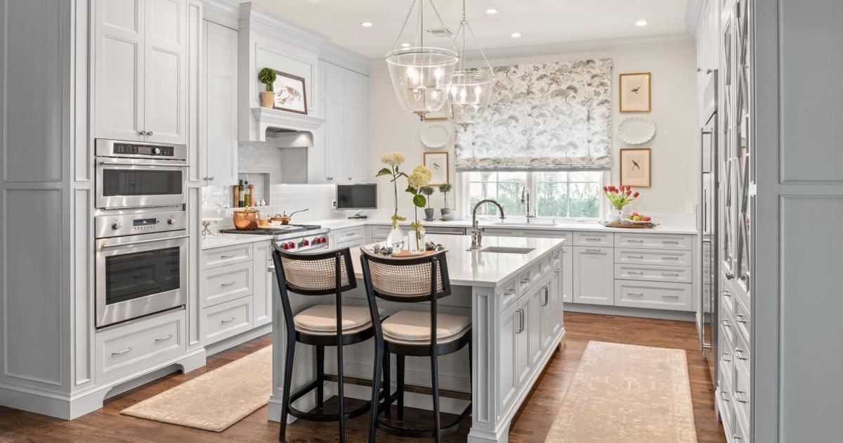 A kitchen with white cabinets and stainless steel appliances and a large island.