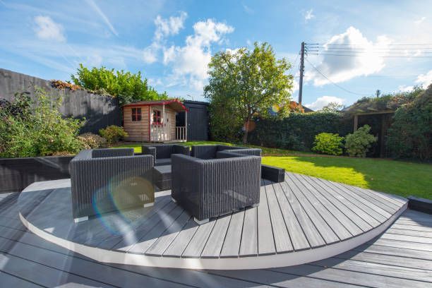 A wooden deck with chairs and a table in a backyard.