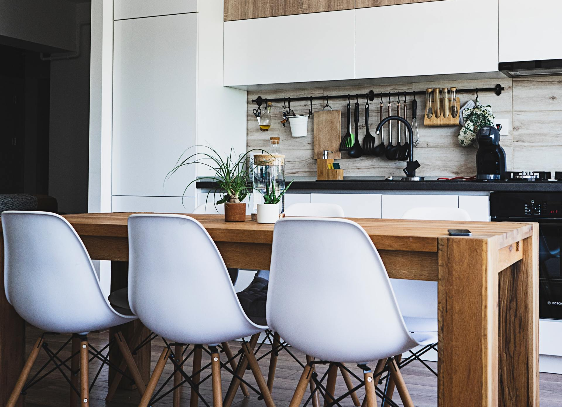A kitchen with a wooden table and white chairs