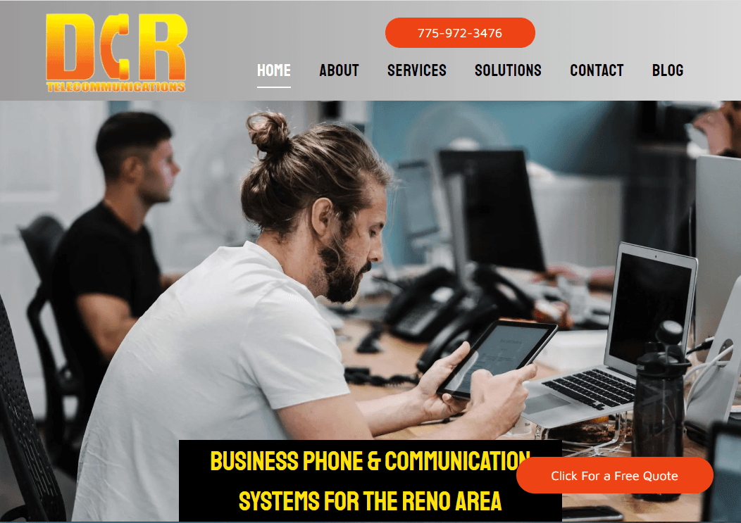 A man is sitting at a desk looking at a tablet.