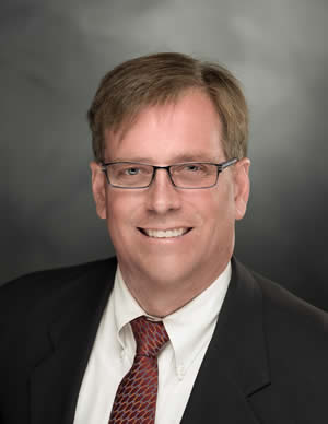 A man in a suit and tie is smiling for the camera.