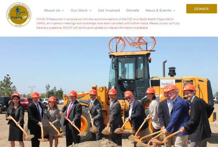 A group of people are shoveling dirt in front of a bulldozer.