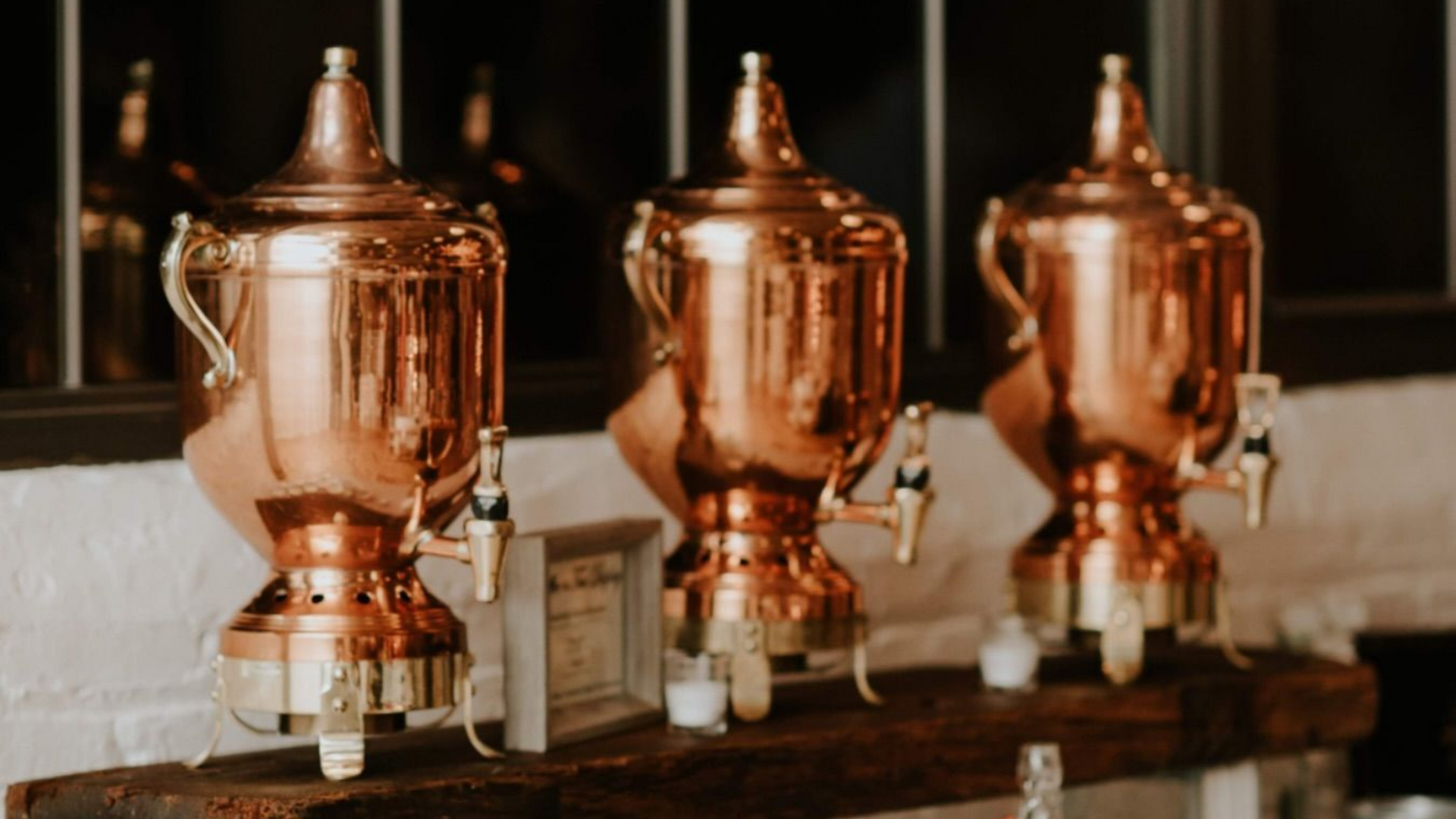 Three copper urns on a shelf, likely serving coffee. Gold spouts and handles for Breakfast Catering