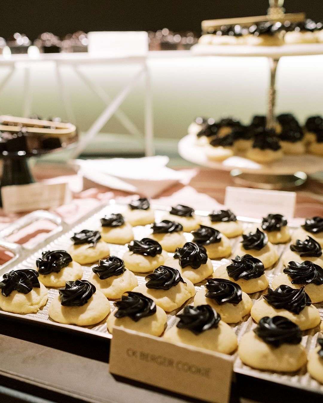 Cookies with dark frosting on a buffet table.