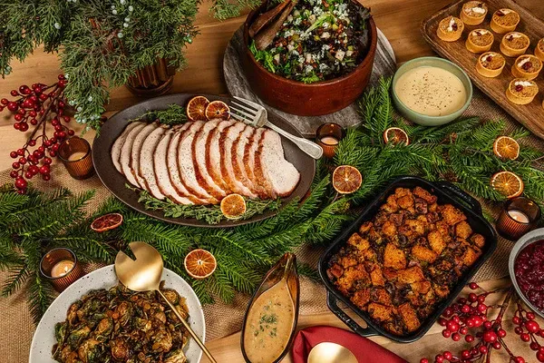Holiday feast: turkey, salad, stuffing, sides, and festive decorations arranged on a table.