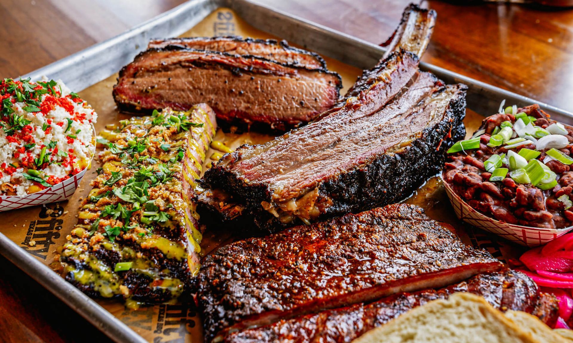 Smoked meats on a tray: brisket, ribs, beans, slaw, and bread.