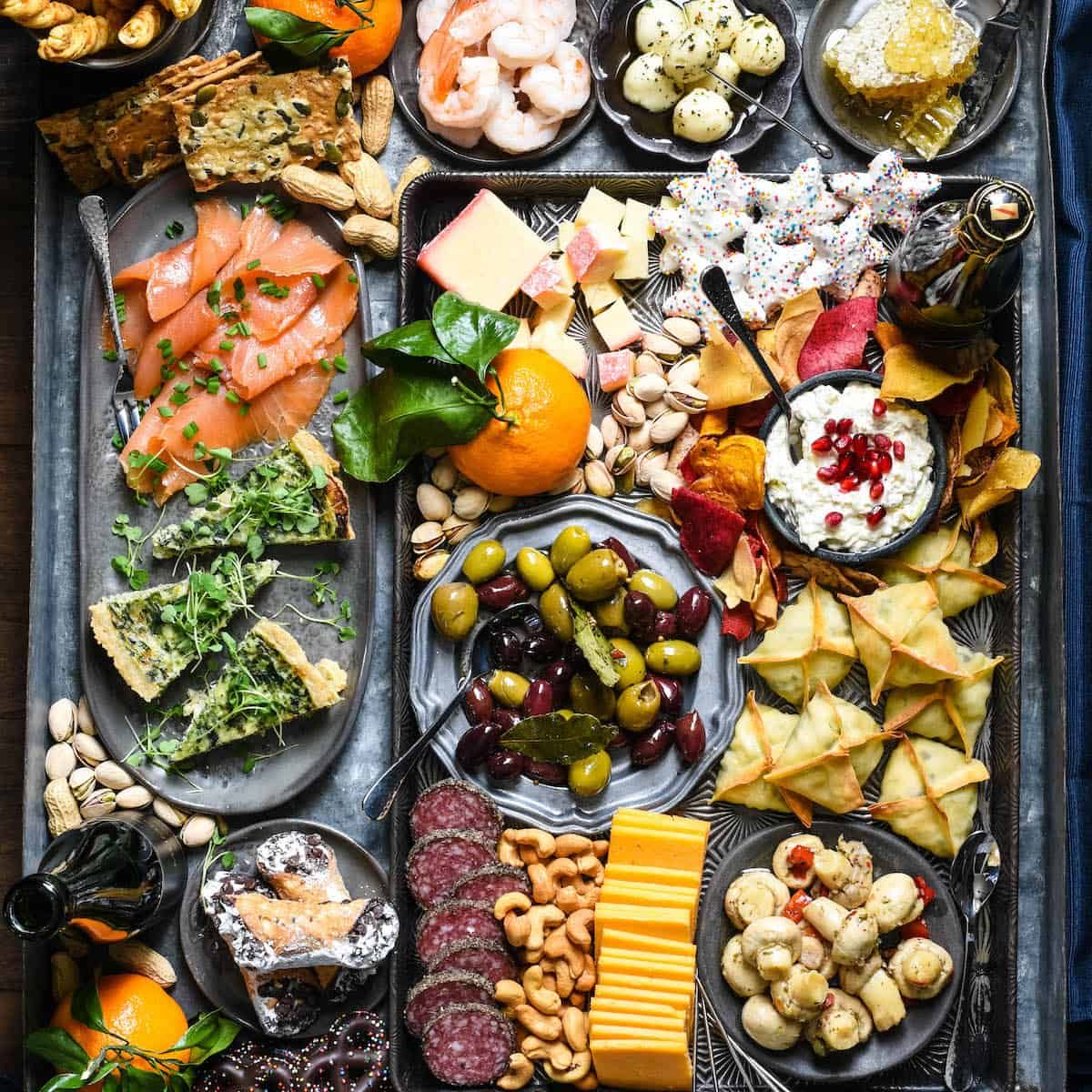 Overhead view of a metal tray filled with various appetizers like cheese, shrimp, and dips.