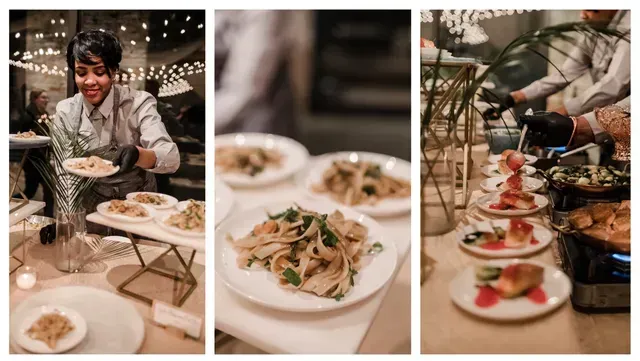 A caterer placing food on plates at an event. Plates of food are on a buffet table, lit by string lights.