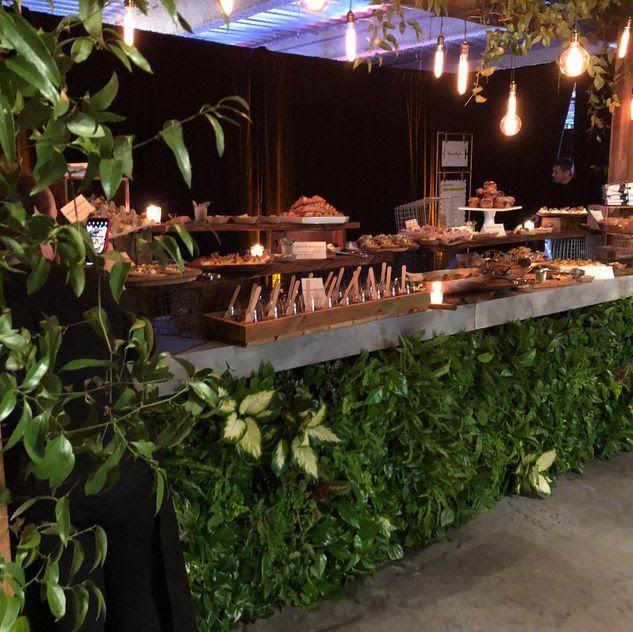 Four women in black outfits pose indoors with smiles.