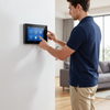 Person using a wall-mounted smart home touchscreen in a living room