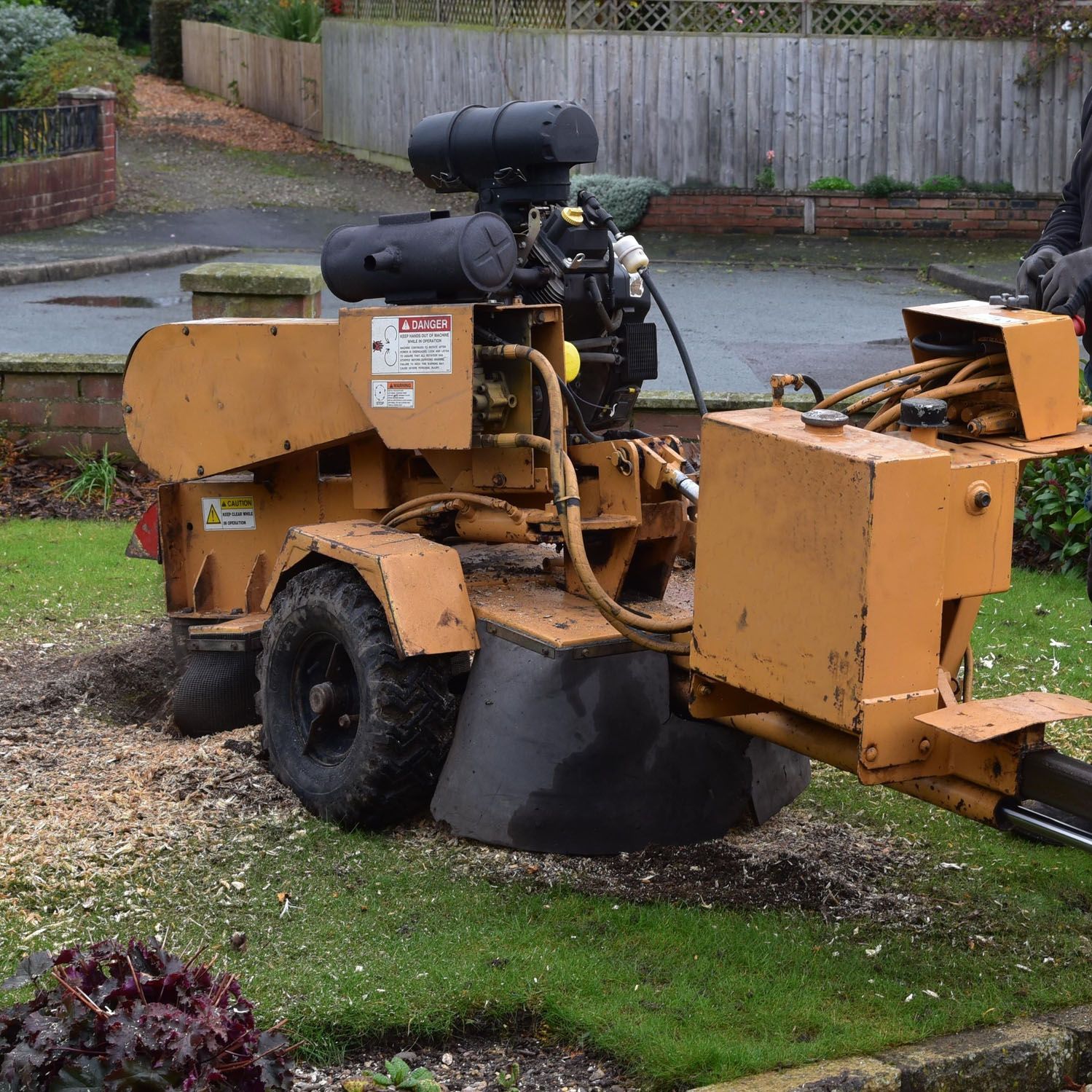 A stump grinder is parked in a lush green yard