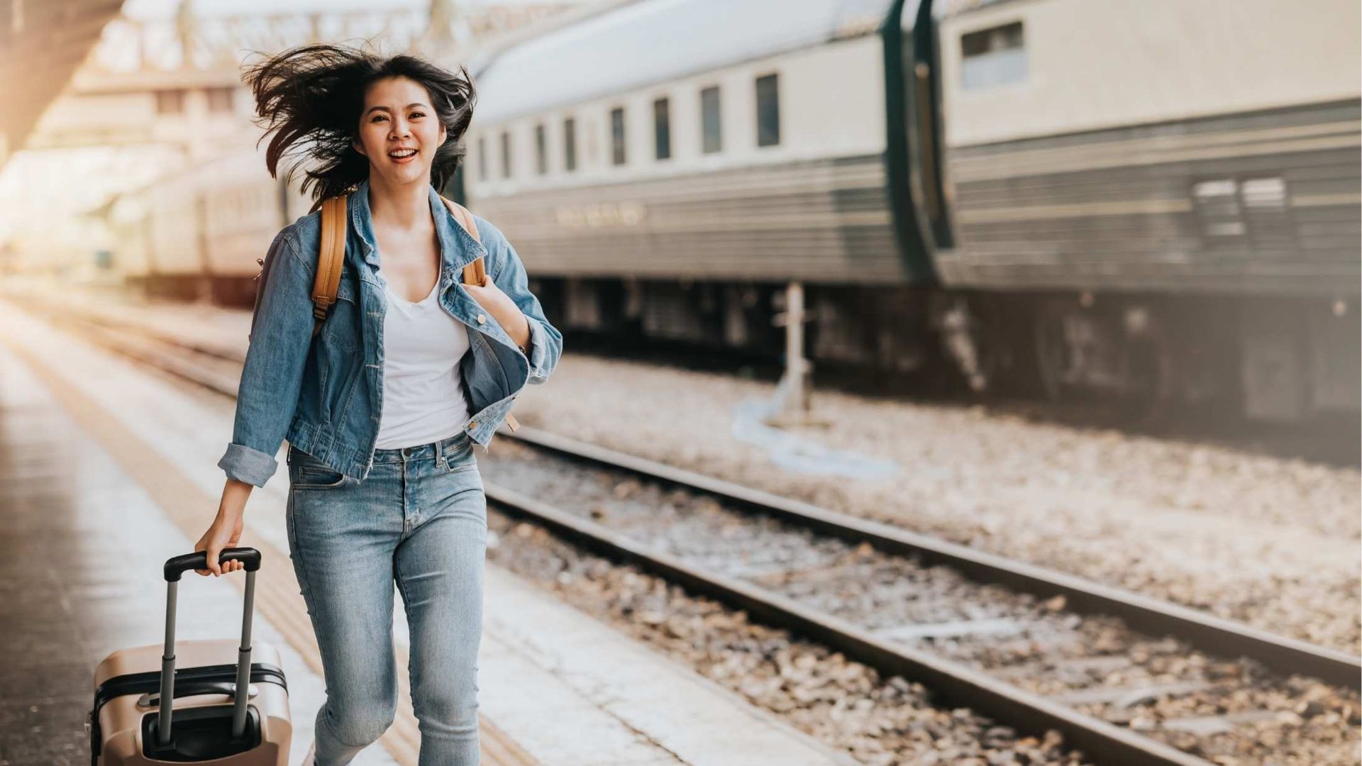 Modern glass and white building with surrounding greenery under a blue sky.