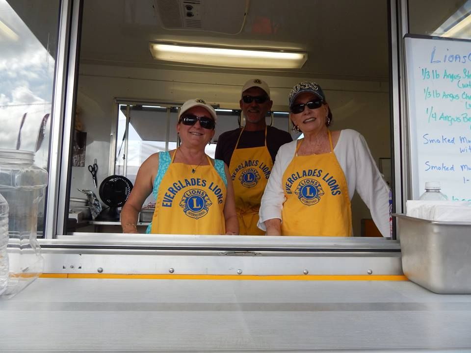 Three people wearing yellow aprons with the word lions on them