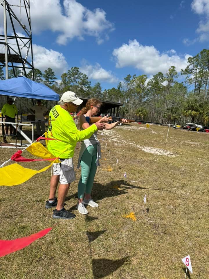 A man is teaching a woman how to fly a kite in a field.