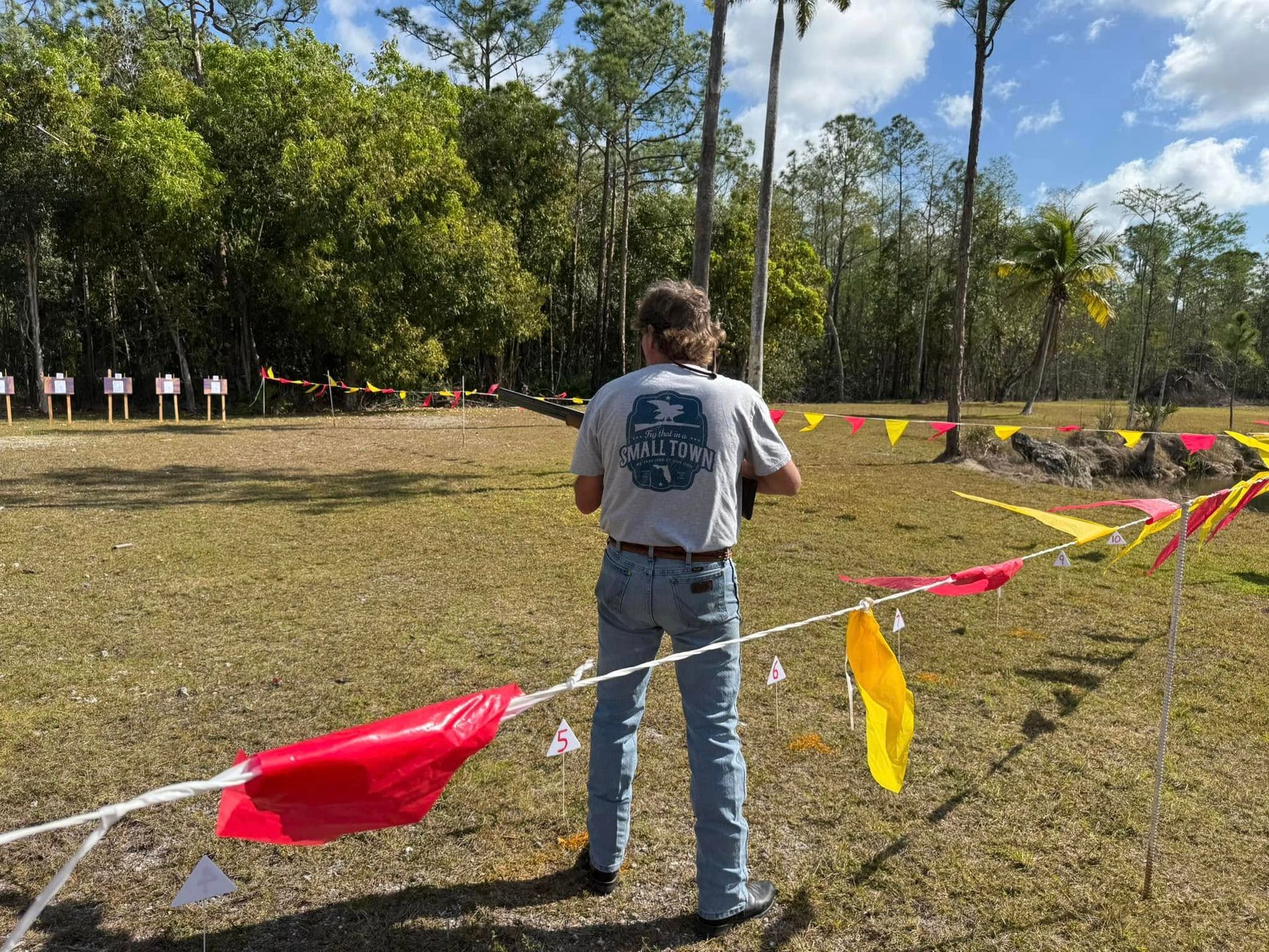 A man is standing in a field with flags hanging from a rope.