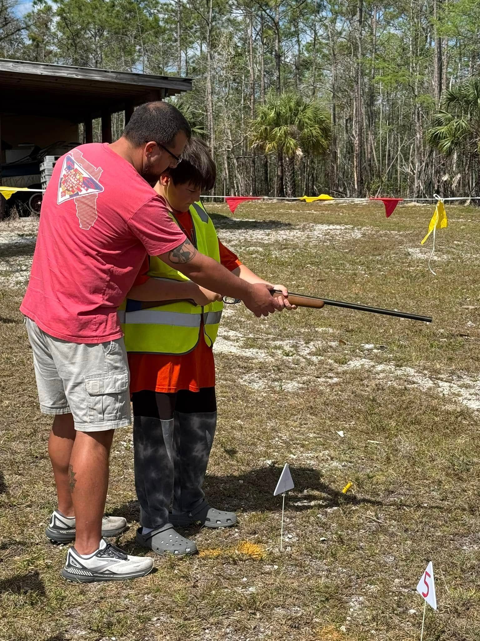 A man and a boy are standing in a field holding a stick.