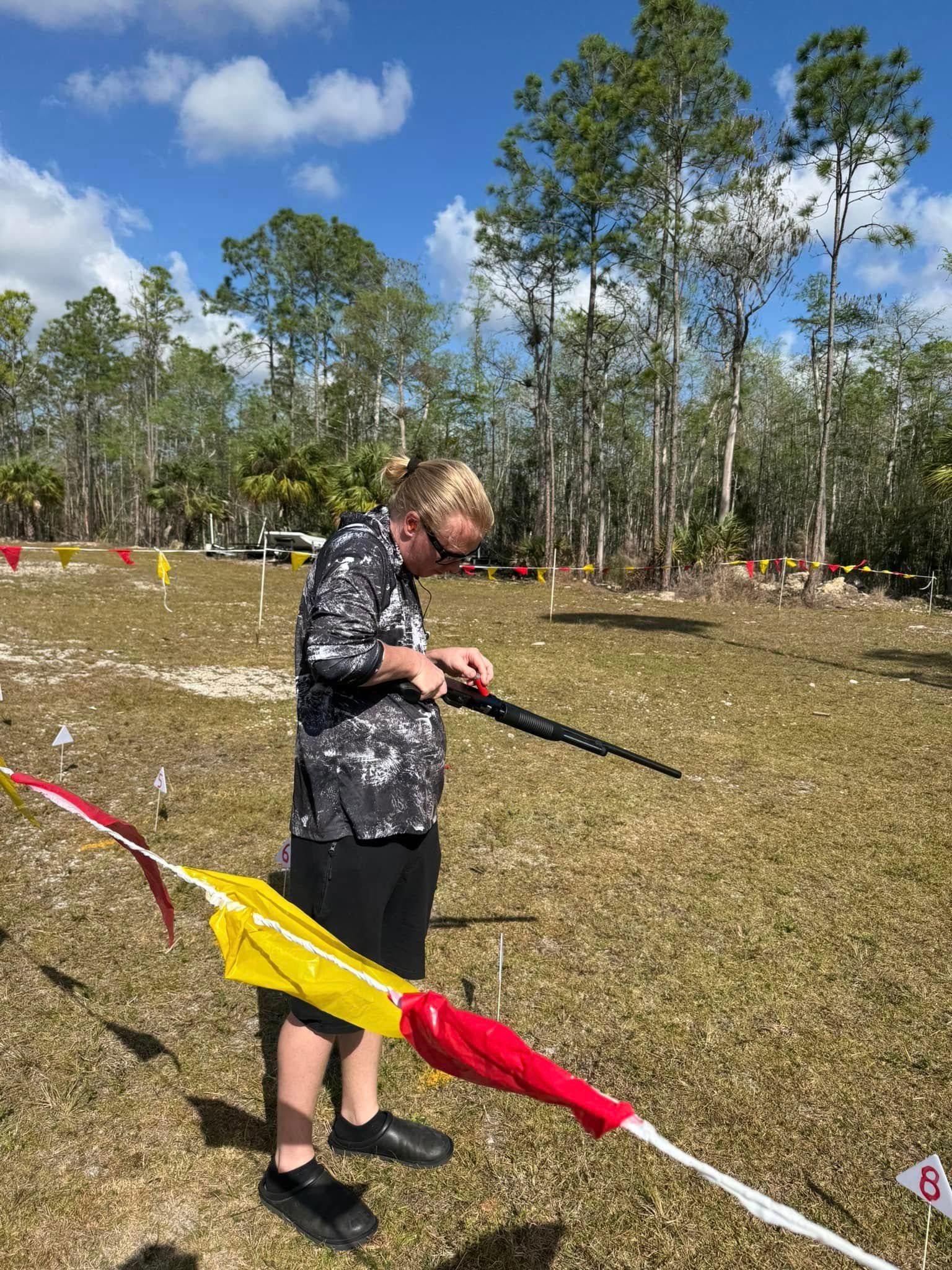 A man is flying a kite in a field with trees in the background.