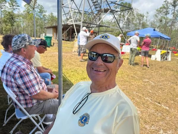 A man wearing sunglasses and a hat is sitting in a chair in a field.