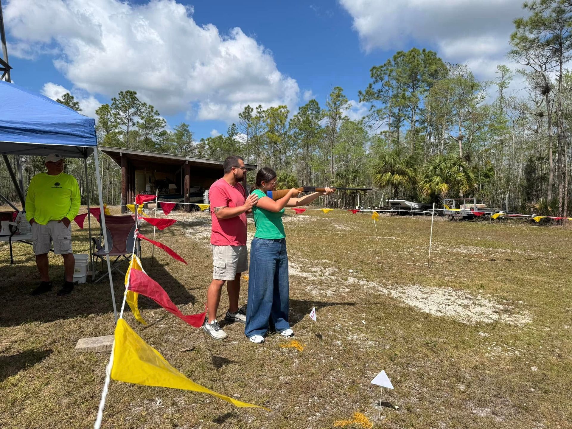 child shooting a gun with help from an adult