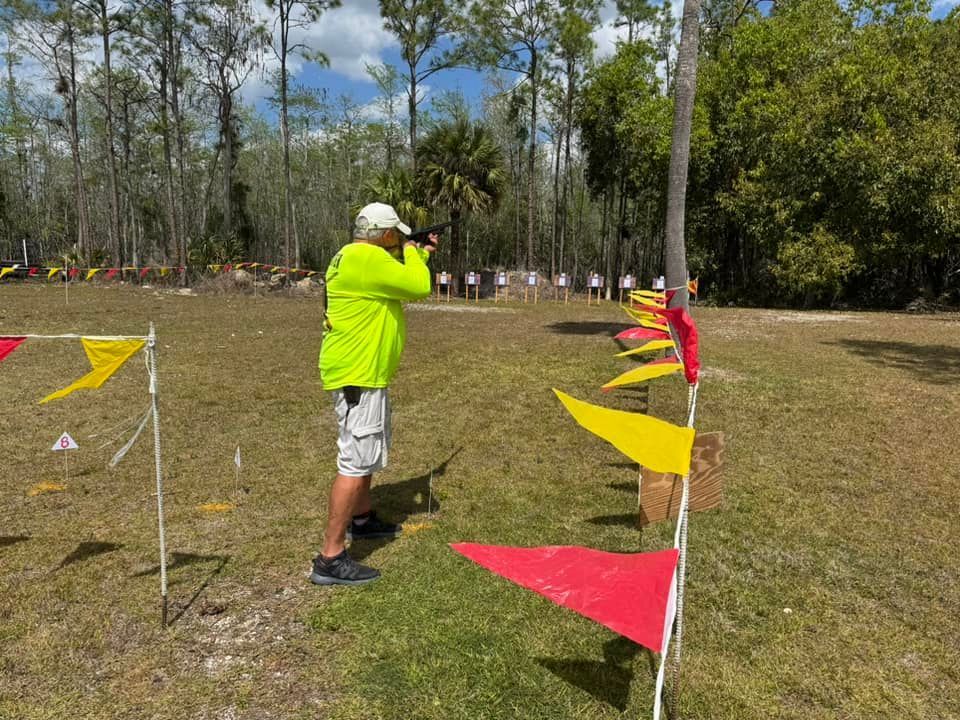 A man in a neon green shirt is standing in a field with flags.