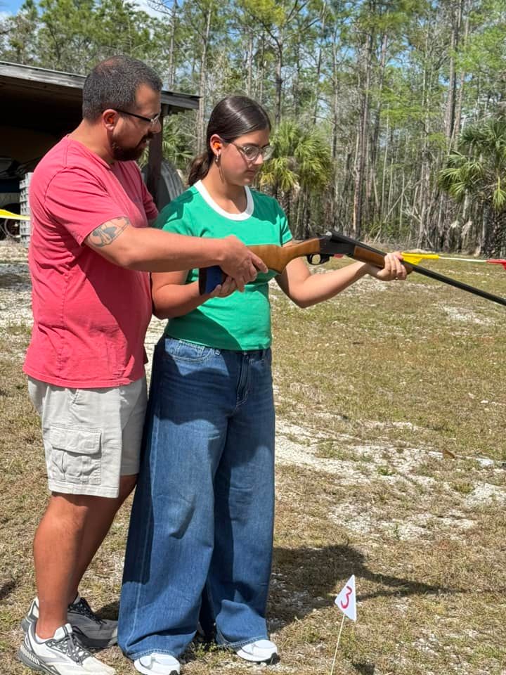child holding a gun with help from an adult
