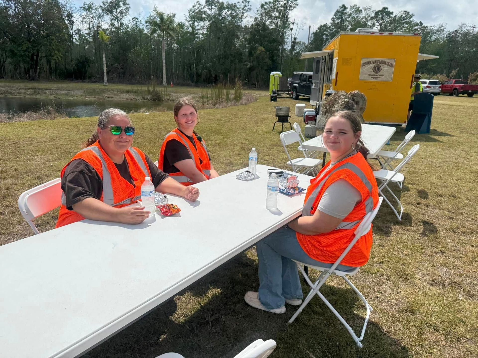 A group of people are sitting at a table in a field.