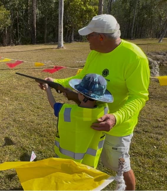child shooting a gun with help from an adult