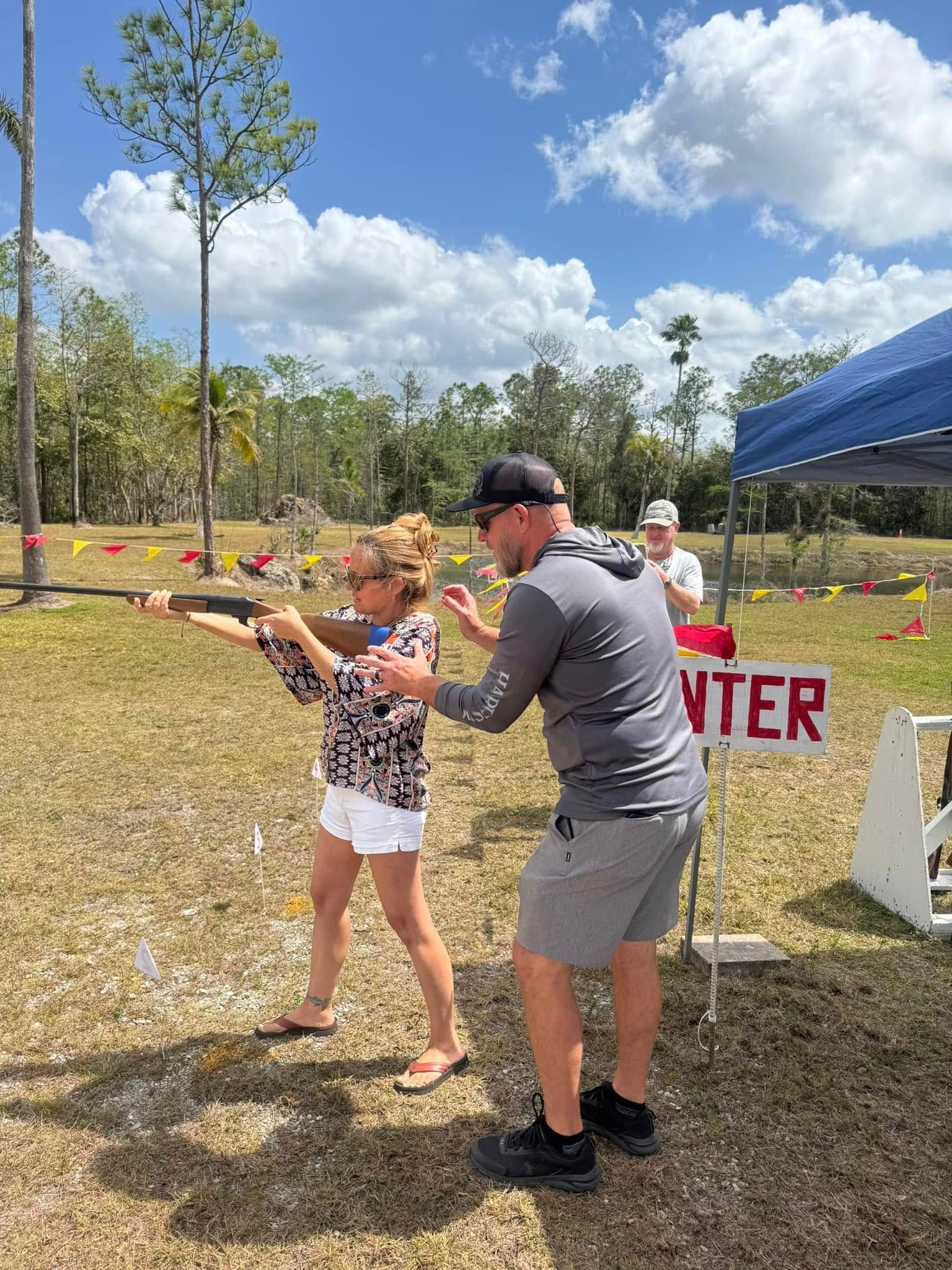 A woman shooting a gun with a man helping her