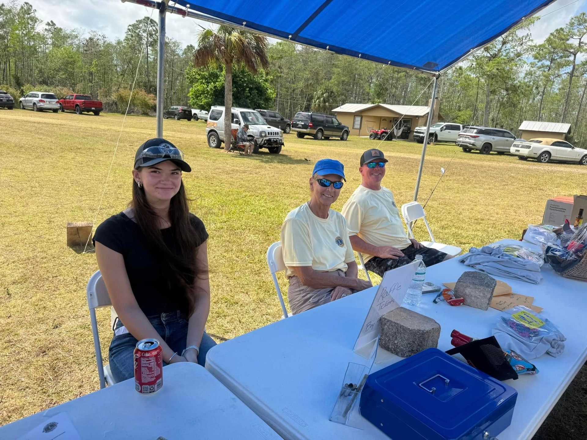 A group of people are sitting at a table in a field.