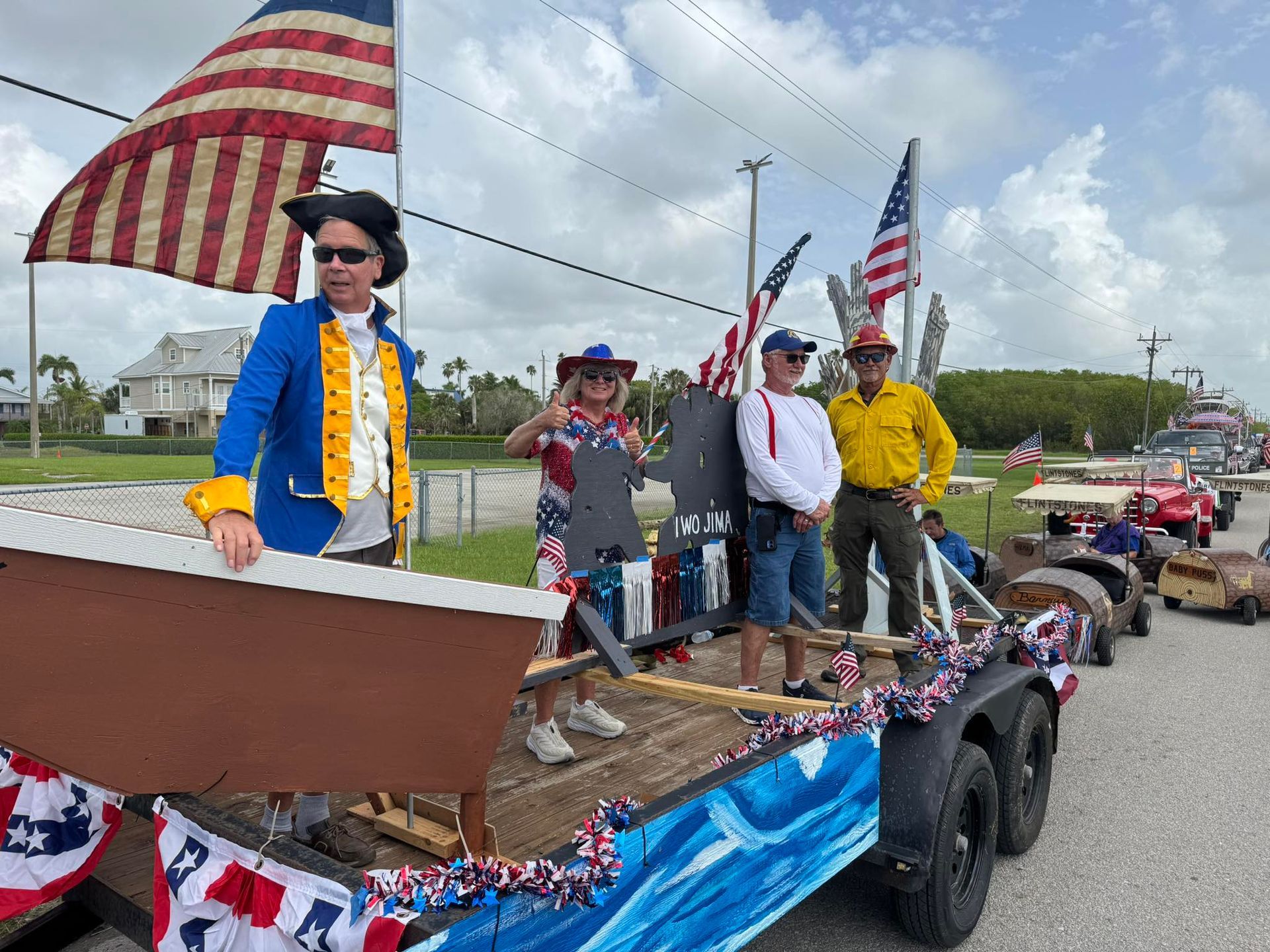 People in patriotic costumes on a float with American flags during a parade.