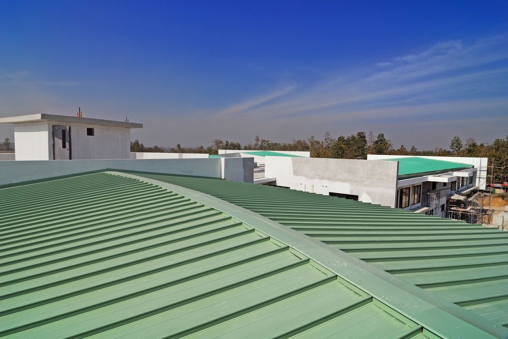 Green metal roof of a building under construction against a blue sky.