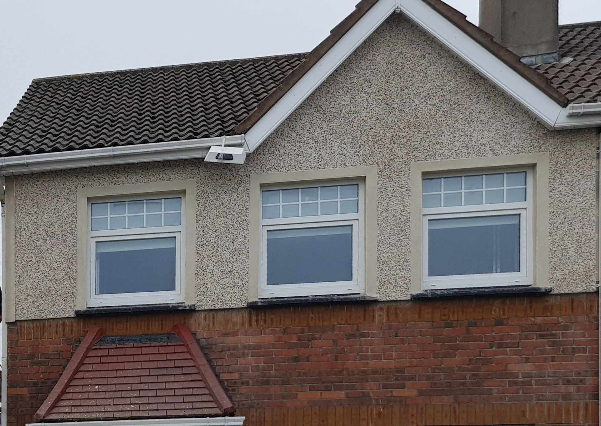 A brick house with a roof and a few windows