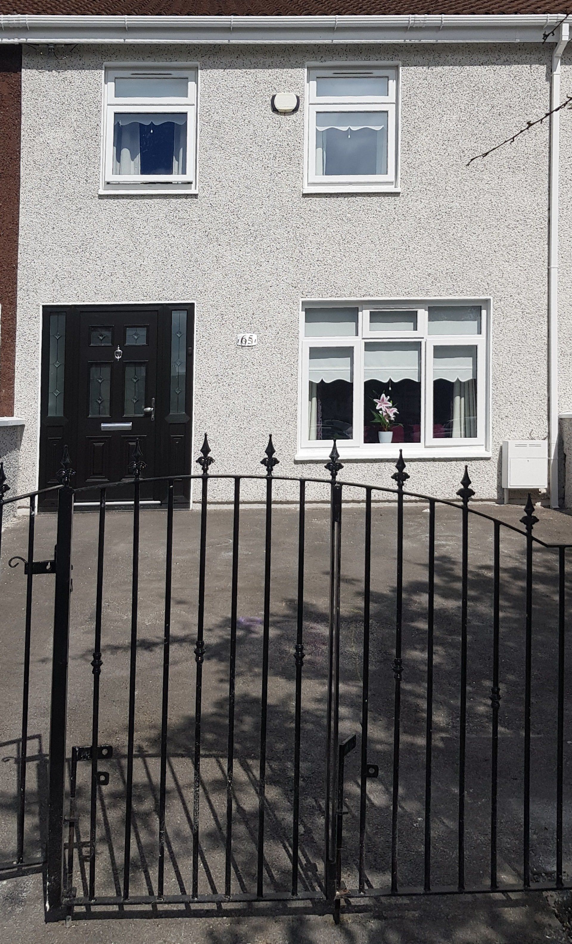 A white house with a black door and a black gate in front of it.