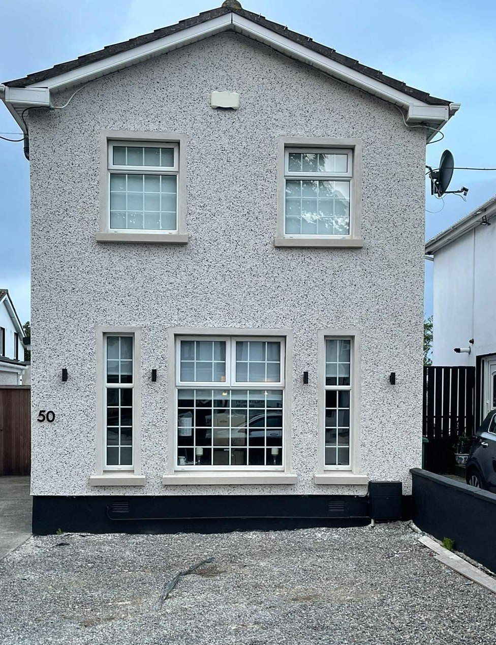 A house with a lot of windows and a car parked in front of it.