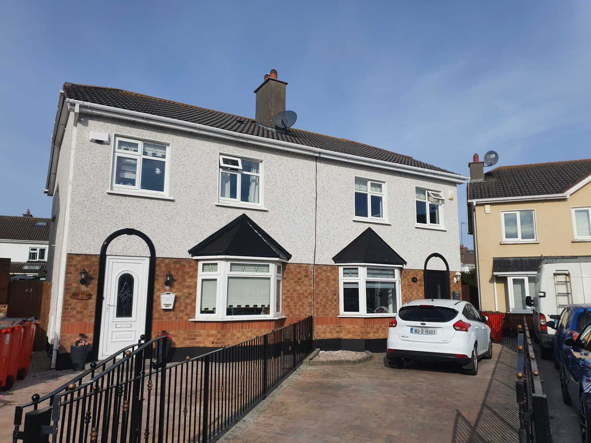 A white car is parked in front of a house.
