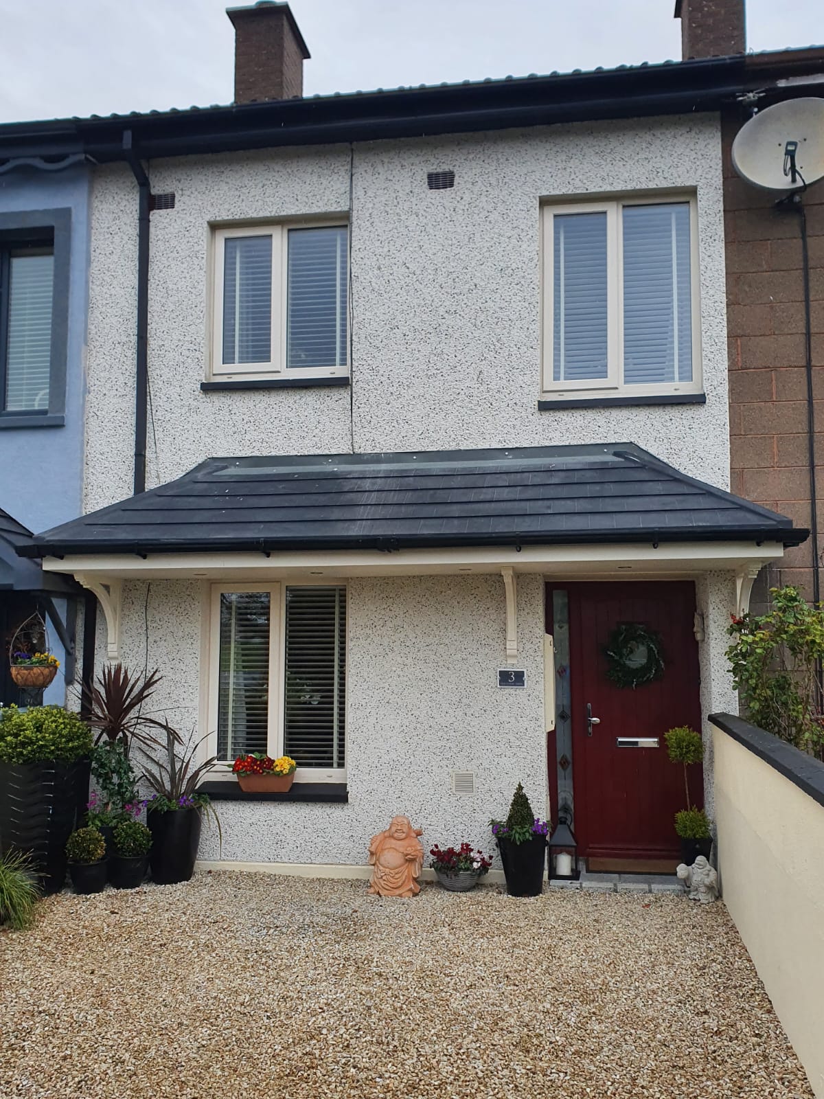 A white house with a red door and a gravel driveway