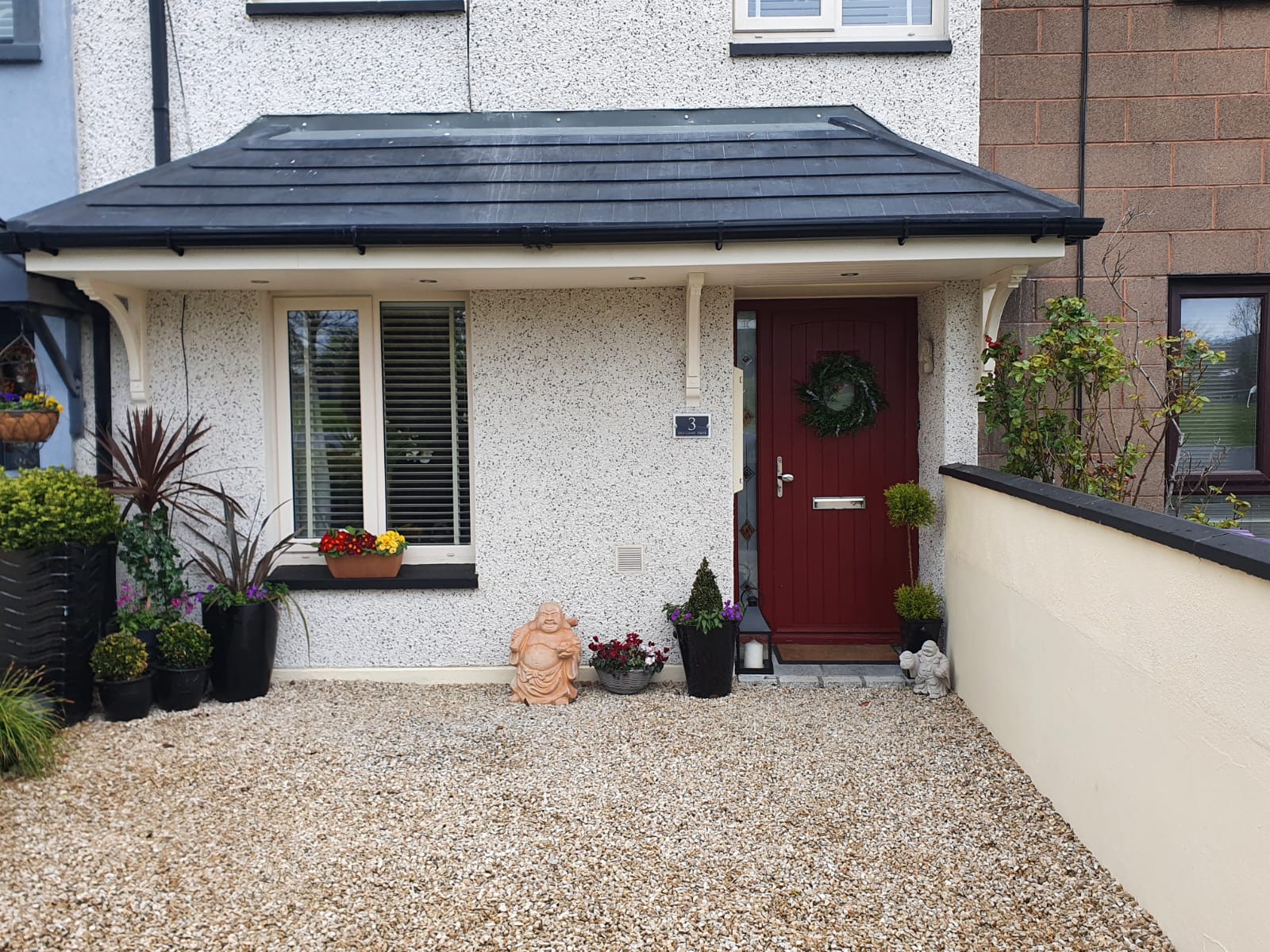 A white house with a red door and a gravel driveway