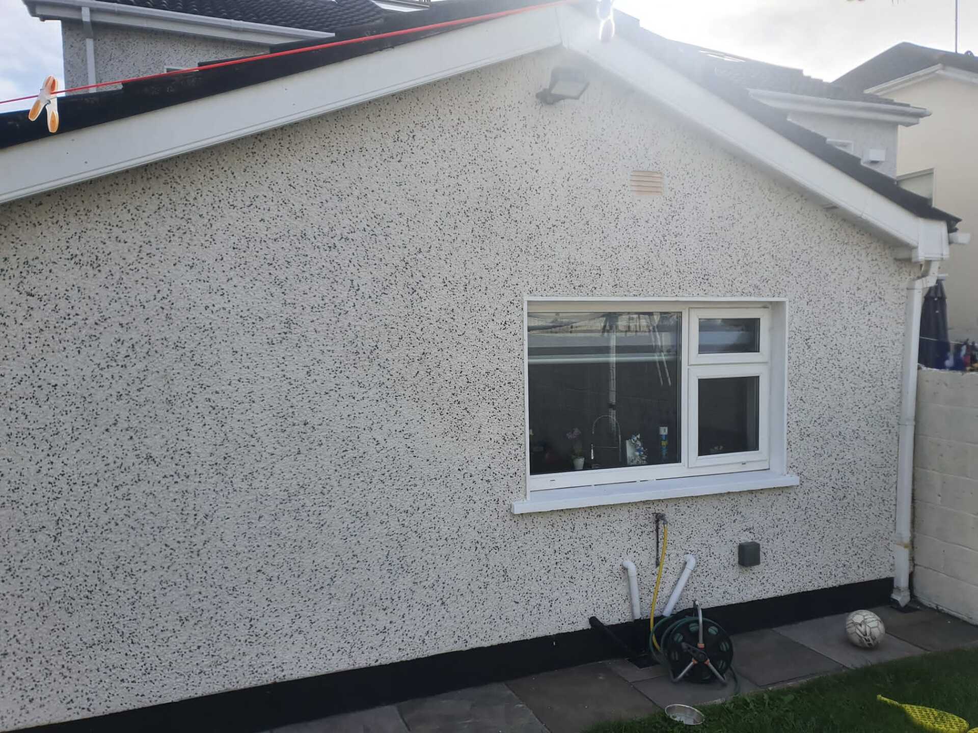 A house with a window and a soccer ball in the backyard.