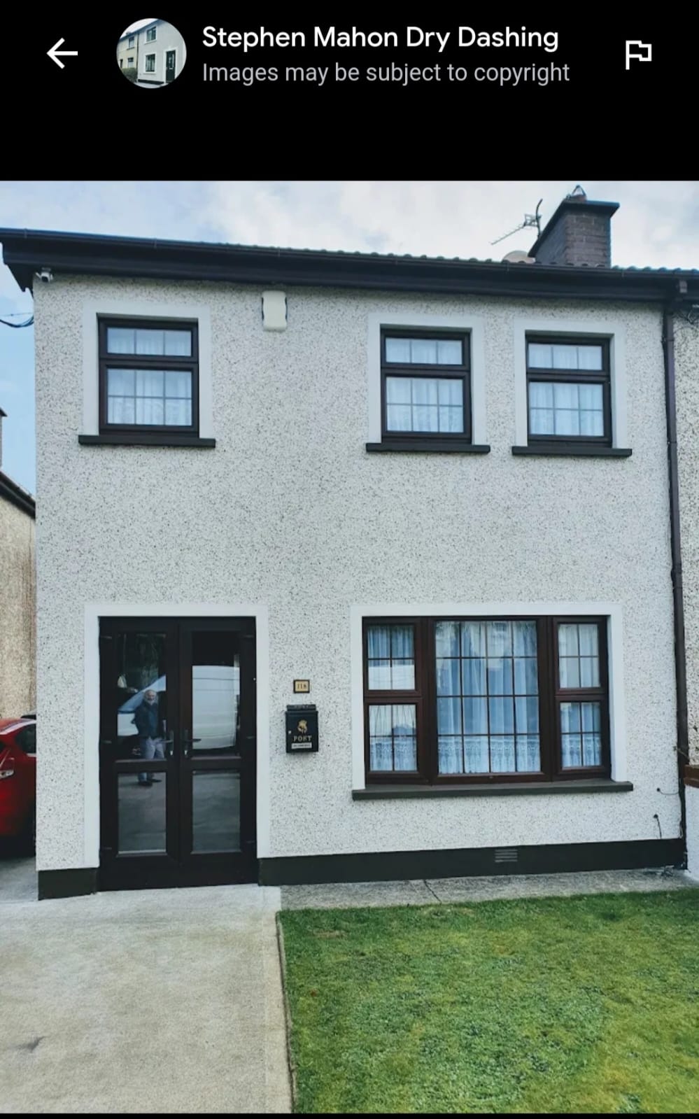 A white house with a lot of windows and a red car parked in front of it