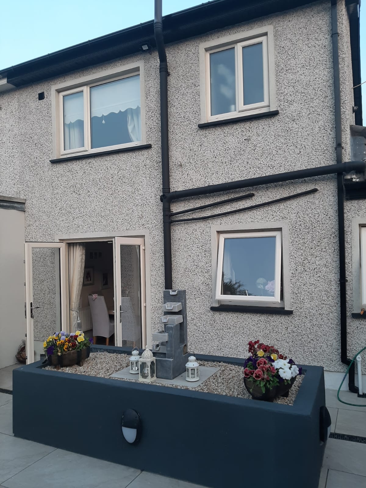 A house with a lot of windows and a planter with flowers in front of it.