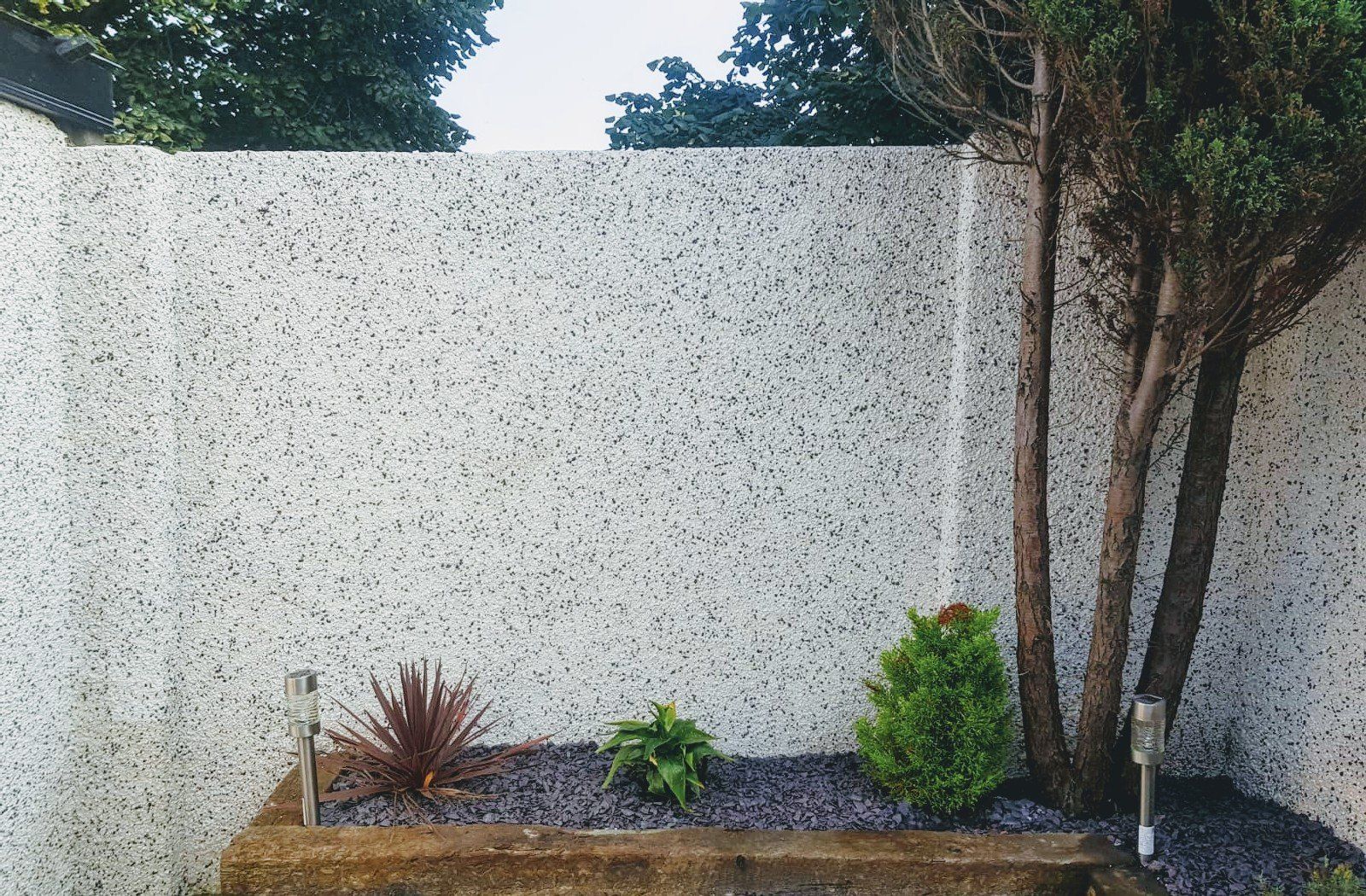 A white wall with a planter in front of it