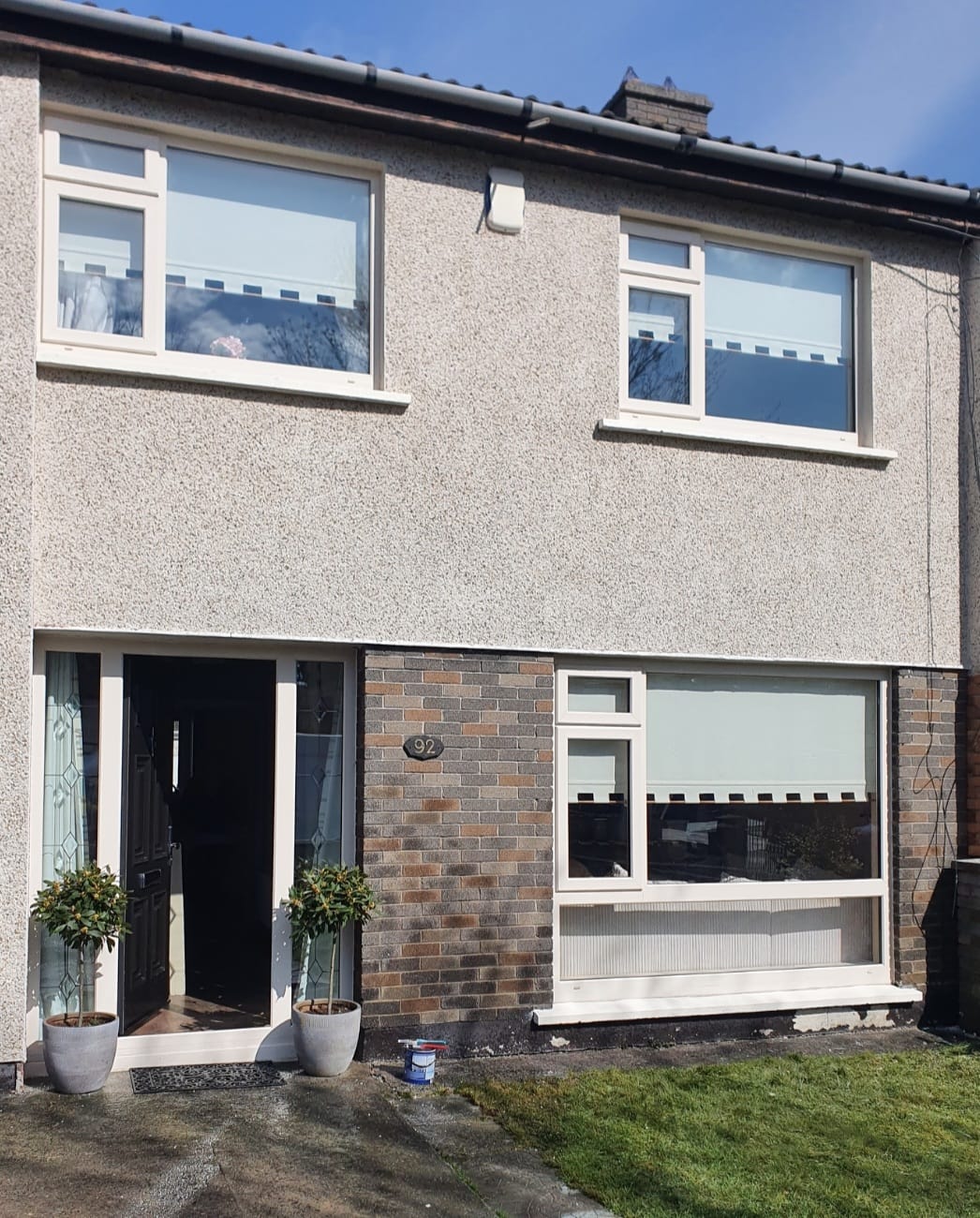 A house with a lot of windows and potted plants in front of it