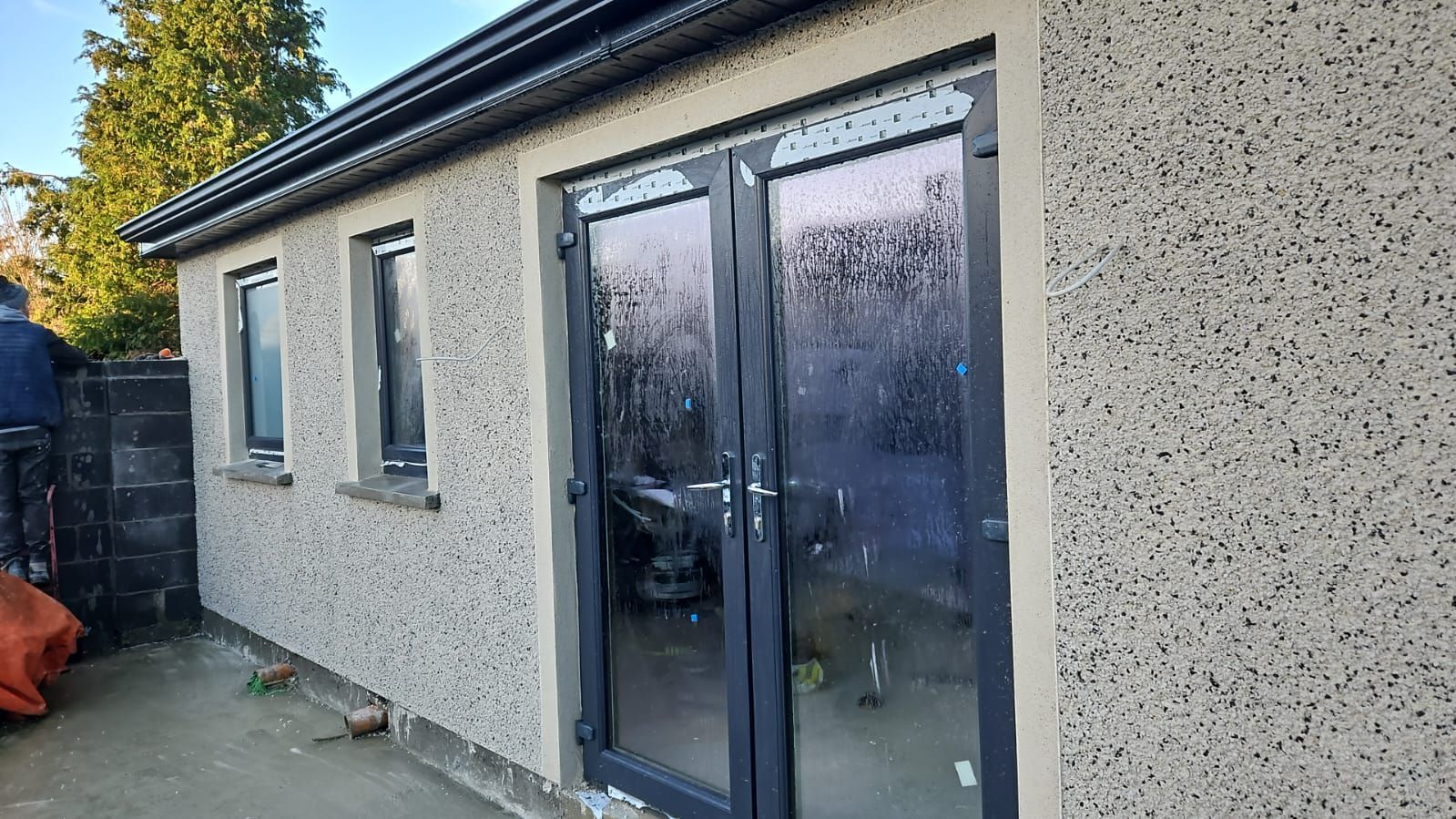A man is standing in front of a building with a lot of windows and doors.