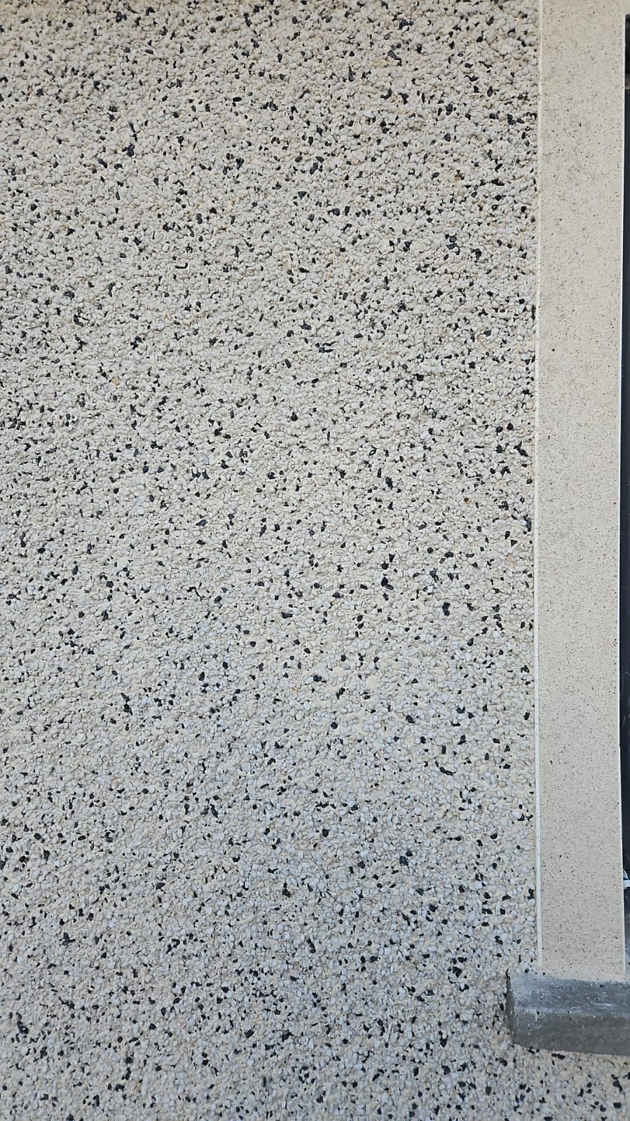 A close up of a white wall with black dots on it.