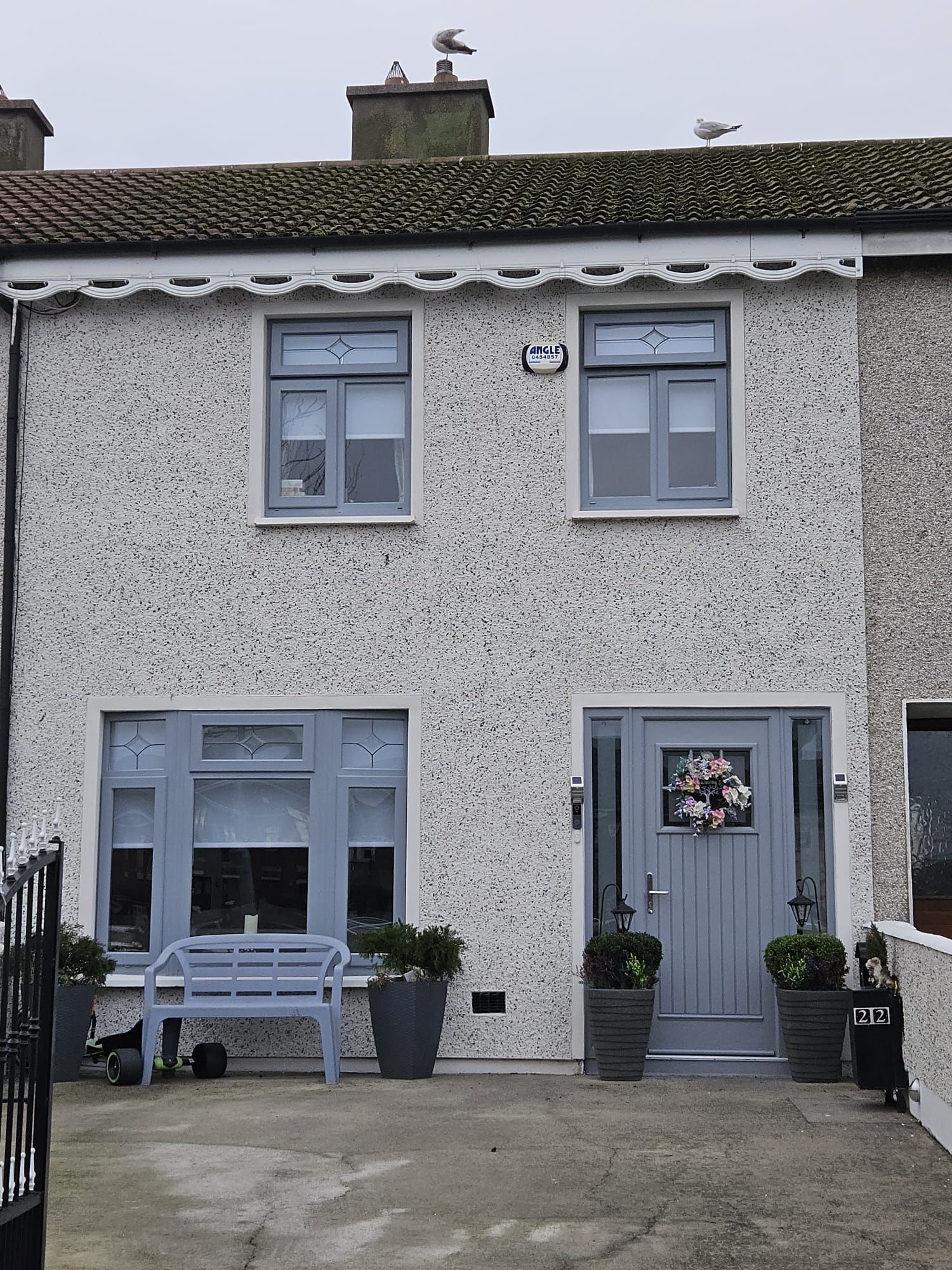 A house with a gray door and a bench in front of it