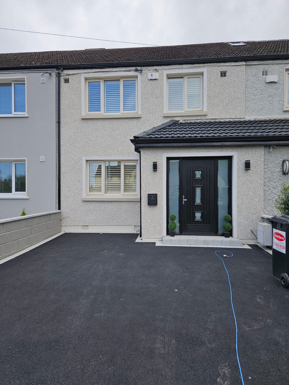 The front of a house with a black door and a black driveway.