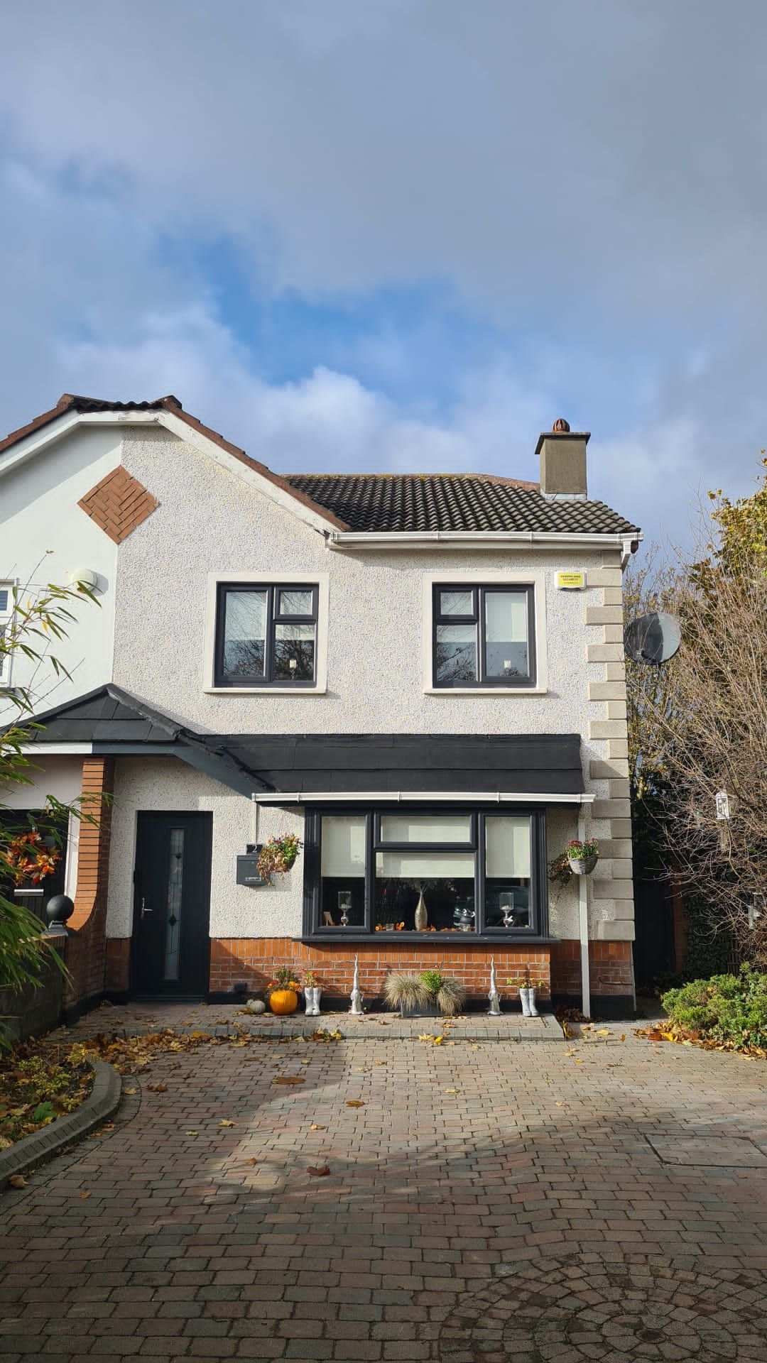 A white house with black windows and a driveway in front of it.