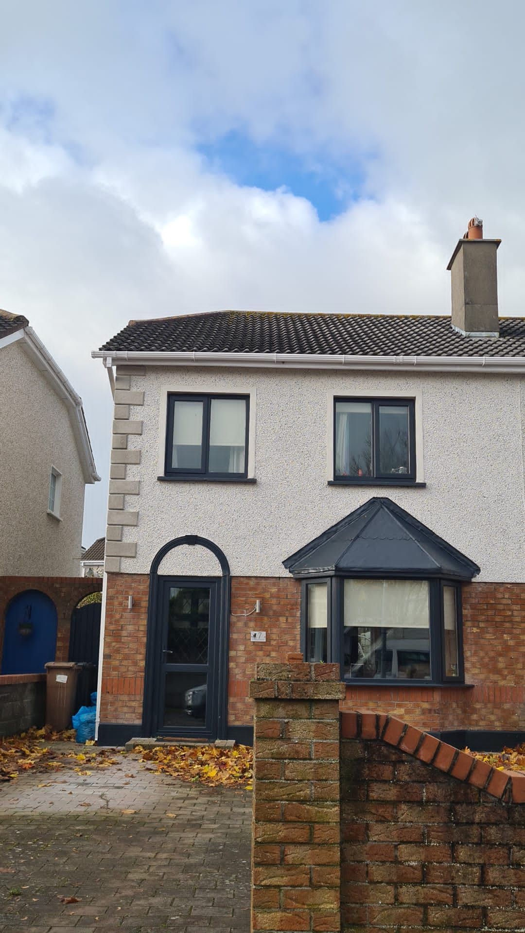 A white house with a brick wall in front of it.