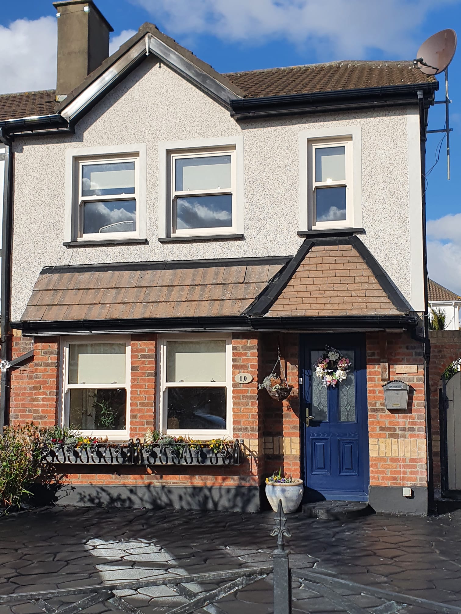 A brick house with a blue door and a satellite dish on the roof