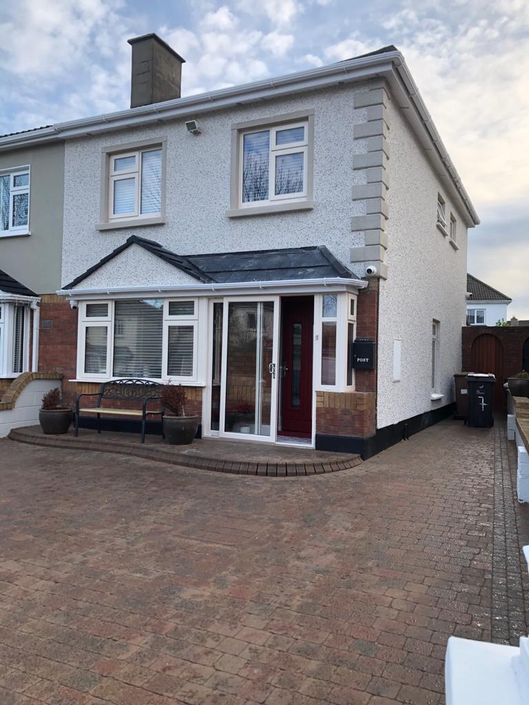 A white house with a red door and a brick driveway